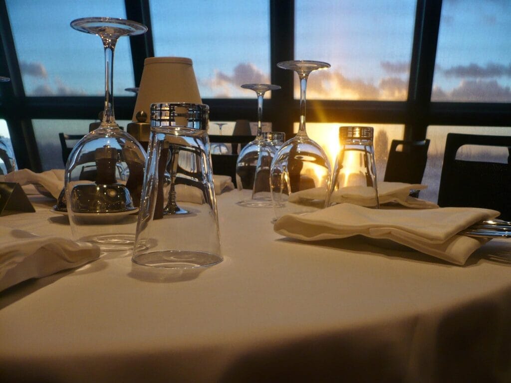 Elegant dining setup on a luxury cruise ship at sunset, offering an affordable luxury experience for families and couples.