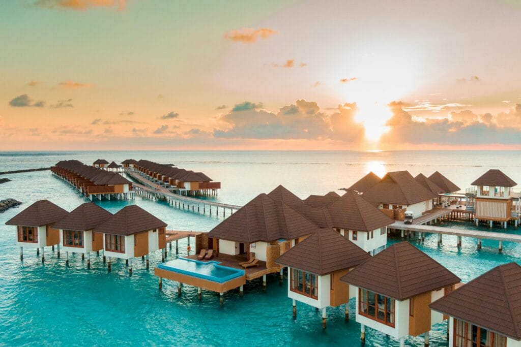 Family relaxing on beach loungers at a luxury resort during sunset, booked in peak season via RCI