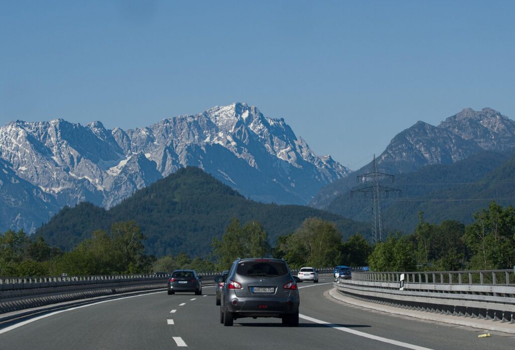alps Austrian autobahn with traffic signs indicating vignette requirement, surrounded by Alpine scenery.