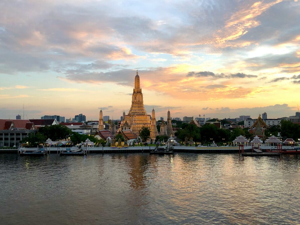 Chao Phraya River at sunset with boat and Bangkok skyline, family-friendly evening scene near ICONSIAM.