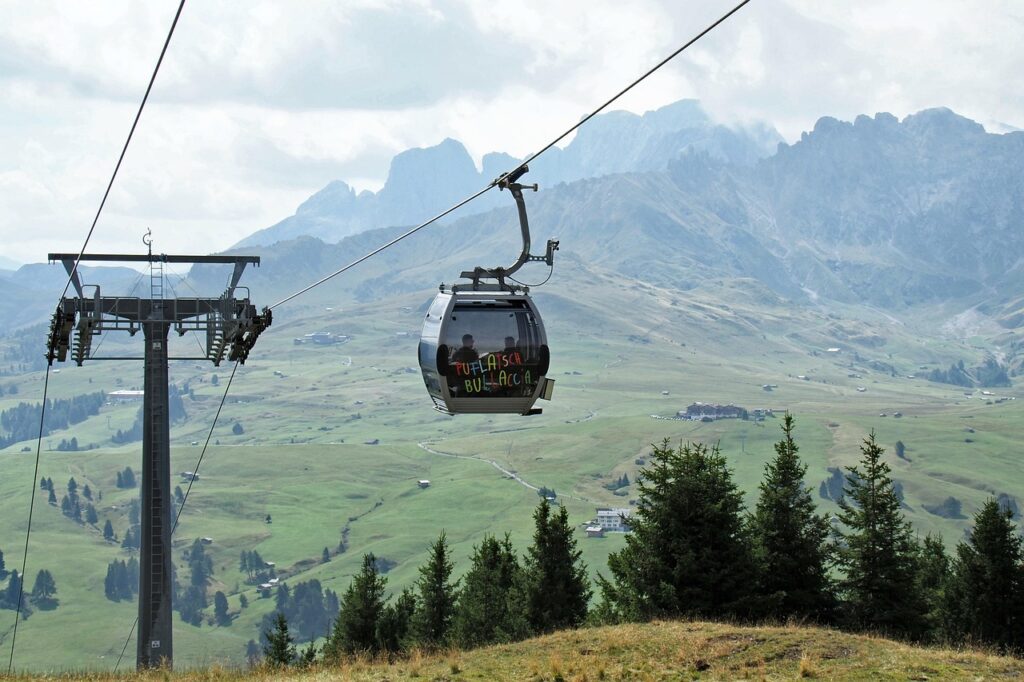 Cable car gliding over the meadows of Alpe di Siusi with Dolomites peaks in the background, South Tyrol, Italy