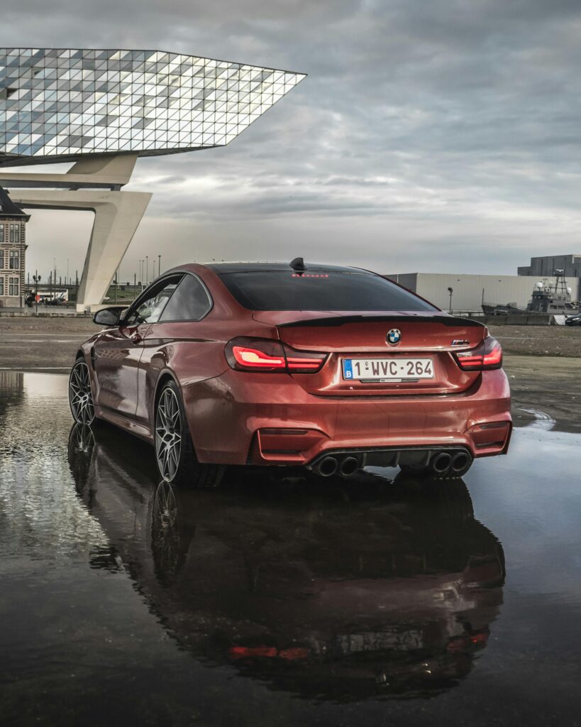 A realistic shot of a couple picking up a sleek black BMW at a European airport rental counter (Frankfurt or Zurich style)